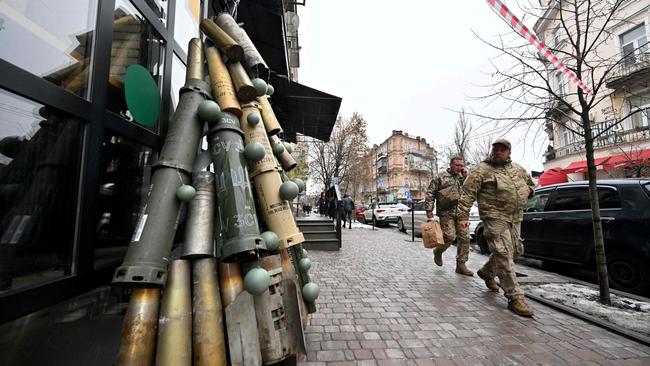 Ukrainian servicemen walk past a symbolic Christmas tree made from spent shells casing and other spent ammunition erected outside a cafe in the centre of Kyiv. Picture: AFP