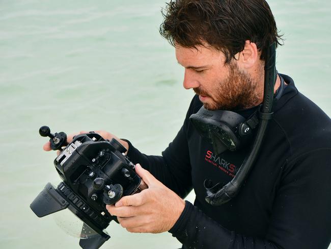 Johnny Gaskell studies his underwater camera before heading out to take photos of the marine wonderland of the Great Barrier Reef.