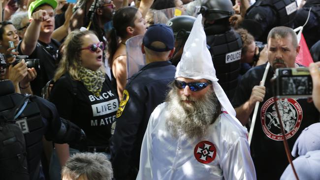 This July 8, 2017 photo shows members of the KKK escorted by police past a large group of protesters during a rally in Charlottesville, Virginia. Picture: Steve Helber