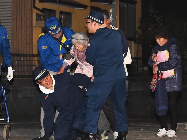 Rescue workers give an elderly woman a piggy back ride after the earthquake. Picture: Getty