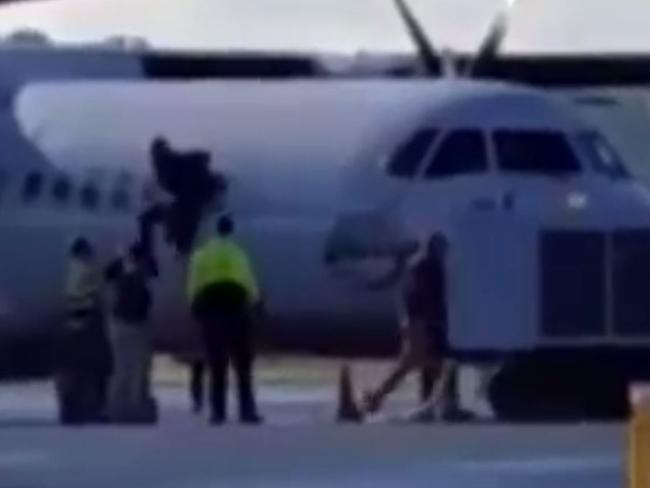 A passenger jumps out of the window of the plane and into the waiting arms of authorities at Albury airport.
