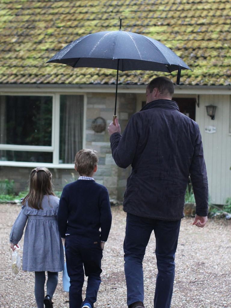 William holding an umbrella for two of his kids as they visit the elderly with essential items during lockdown.