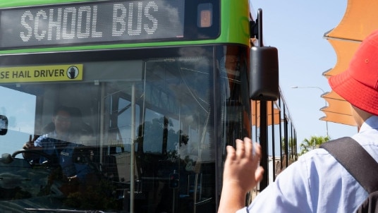 A student waves down a school bus on the Gold Coast.