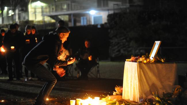 A woman lays a candle at a gathering to support the family of Qi Yu in Berowra. Picture: Jake McCallum