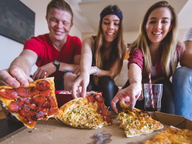 A group of friends eating takeaway pizza at home. Picture: Supplied.