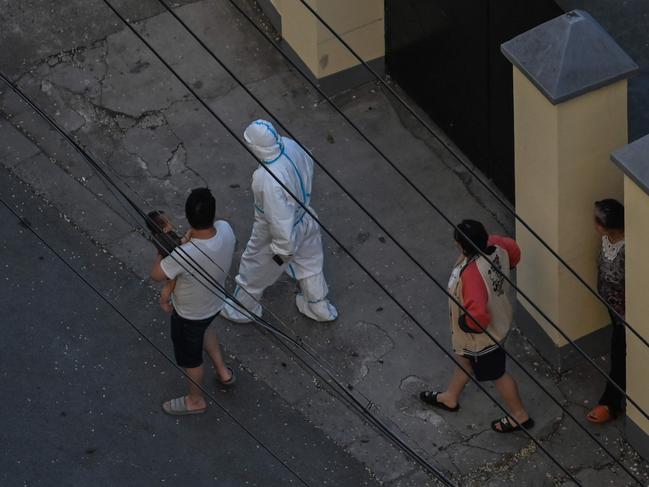 A worker wearing personal protective equipment (PPE) walks with residents during a lockdown in the Jing'an district in Shanghai. Picture: AFP