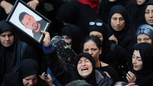 A relative of Samer Huhu, who was killed in a twin bombing attack that rocked a busy shopping street in Beirut, waves his portrait as she mourns during his funeral on November 13, 2015. Lebanon mourned 44 people killed in the bloodiest such attack in years. Picture: Joseph Eid / AFP