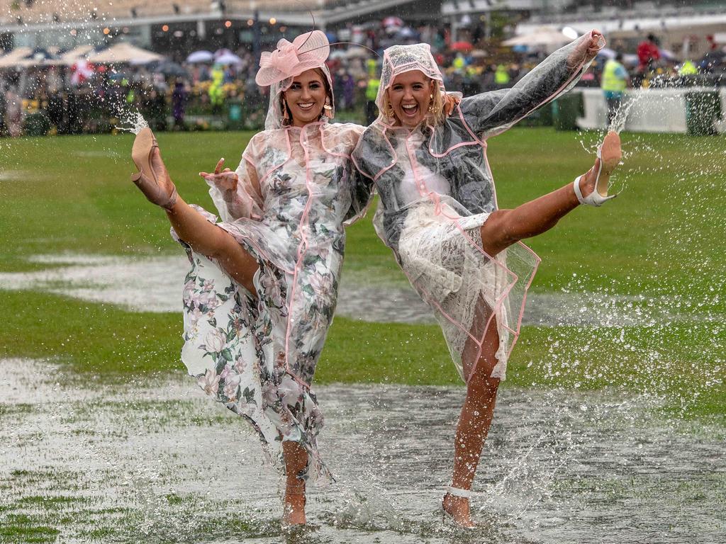 Sisters Taylor Harrang, 22, and Emma Harrang, 23 didn’t let the rain at Flemington ruin their trackside celebrations. Picture: Jason Edwards