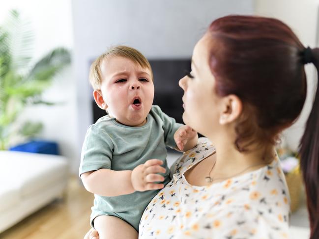 A mother holding child baby on the living room. The baby is sick having some cough