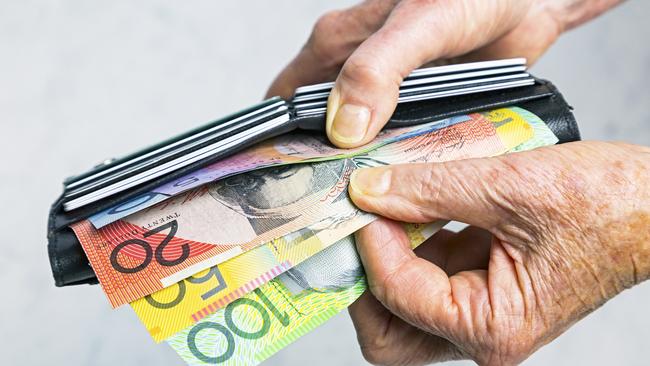 Close-up, senior female hands taking Australian banknotes (cash, currency) from purse containing many credit cards.  Horizontal, studio, copy space. Money generic