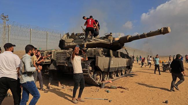 Palestinians take control of an Israeli tank after crossing the border fence with Israel from Khan Yunis in the southern Gaza Strip. Picture: AFP