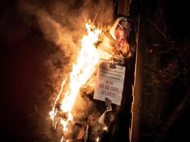 A burning effigy representing Danish Prime Minister Mette Frederiksen with a sign around its neck reading “She must be put down” as a radical group protests restrictions introduced by the Danish government. Picture: AFP / Denmark OUT