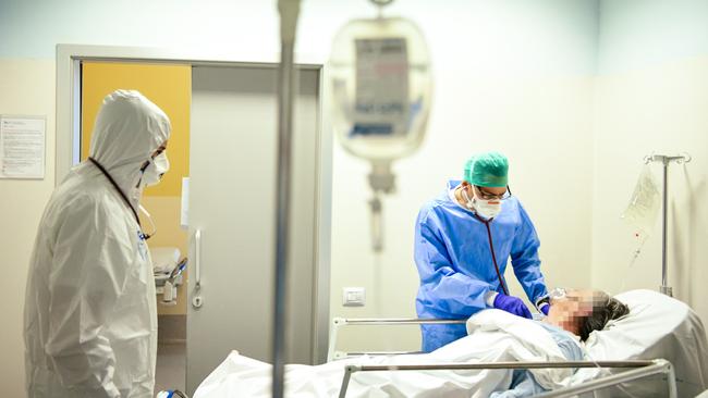 A member of the medical staff comforts a patient infected by coronavirus in Bergamo, Italy. Picture: AFP