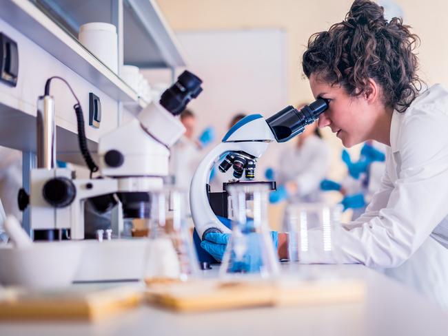 Scientist in lab doing research and using lab machines, test tubes, microscope and every laboratory equipment