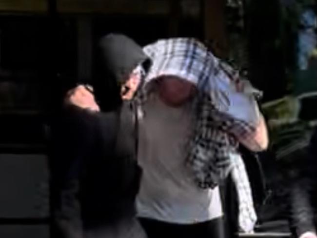 Nathan Bernhard leaving Nowra Police Station, hidden under blanket. Picture: Tom McGann