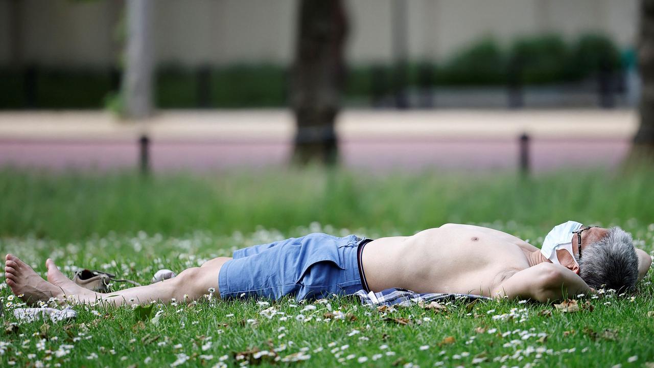 A man wearing a face mask sunbathes in London’s St James’ Park. Picture: Tolga Akmen/AFP