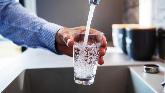 Mature male hand  pouring a glass of water from tap in the kitchen sink