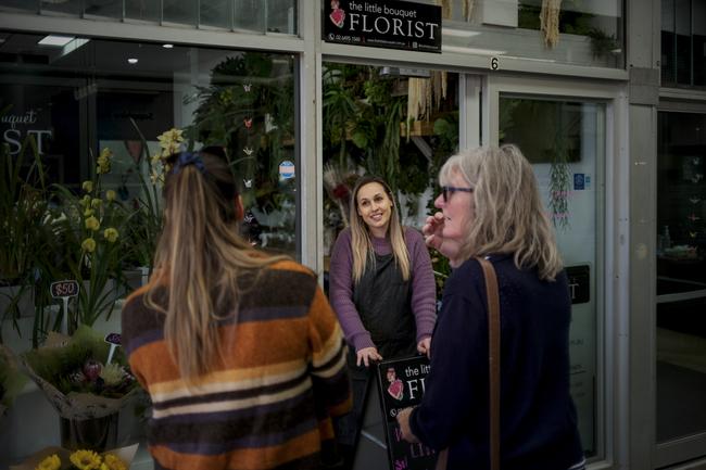 Jasmine Maree Fleet, 35, owner of The Little Bouquet florist, greets customers at the front of her shop in in Merimbula, NSW. Since COVID-19 social distancing restrictions have been implemented, Jasmine doesn’t allow customers into the shop and has had numerous supply issues due to the disruption of the freight network from Melbourne. Picture by Sean Davey.