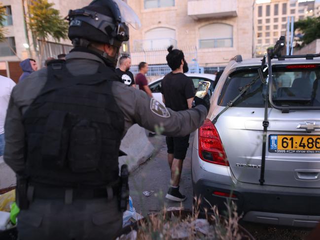 An Israeli border guard takes a picture of a bullet hole in a car in the east Jerusalem neighbourhood of Sheikh Jarrah. Picture: AFP