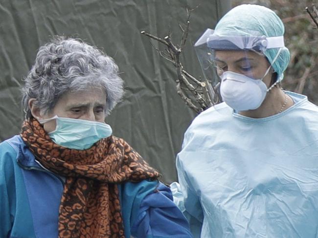 An elderly patient is helped by a doctor at one of the emergency structures that were set up to ease procedures at the Brescia hospital, northern Italy, Thursday, March 12, 2020. Italians woke up to yet further virus-containment restrictions after Premier Giuseppe Conte ordered restaurants, cafes and retail shops closed after imposing a nationwide lockdown on personal movement. For most people, the new coronavirus causes only mild or moderate symptoms, such as fever and cough. For some, especially older adults and people with existing health problems, it can cause more severe illness, including pneumonia. (AP Photo/Luca Bruno)