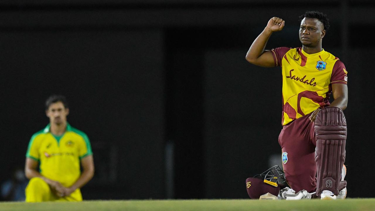 Evin Lewis of West Indies takes a knee before the start of the match, alongside Aussie quick Mitch Starc. Picture: Randy Brooks/AFP