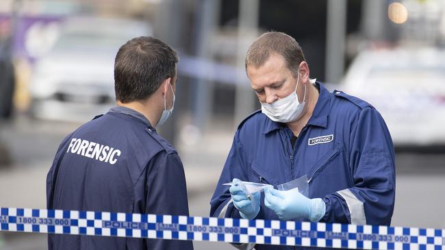 Forensic police examine a bullet casing at the scene of a multiple shooting outside Love Machine nightclub in Prahran. 