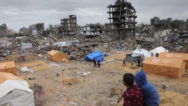 Palestinian children sat on a sand mound overlooking tents set up amid destroyed buildings in Jabalia, in northern Gaza, on Thursday. Picture: Bashar Taleb/AFP/Getty Images