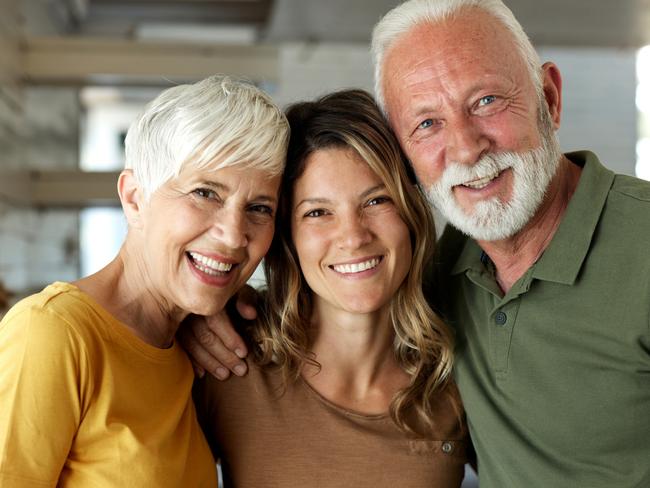 Happy adult daughter enjoying with her mature parents at home and looking at camera; Bank of Mum and Dad generic money