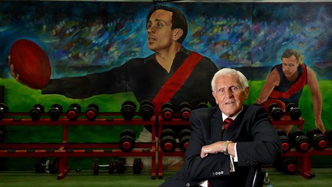 Essendon champion Jack Jones at Windy Hill, in front of a mural of the legendary Dick Reynolds.