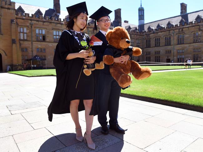 Students from China pose for family photos after graduating from a course in commerce at Sydney University on October 12, 2017. Australia is tightening requirements for foreign students in a bid to improve standards across the country's Aus$28 billion ($22 billion) international education market, the government said on October 12. / AFP PHOTO / William WEST