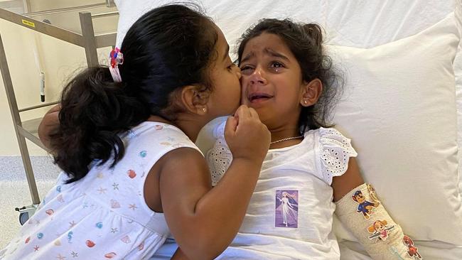 The youngest daughter of the ‘Biloela family’, Tharnicaa, was medically evacuated to Perth after being hospitalised on Christmas Island. Kopika, her sister, comforts her with a kiss. Supplied: Change.org