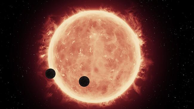 An artist's illustration shows two Earth-sized planets, TRAPPIST-1b and TRAPPIST-1c, passing in front of their parent red dwarf star. Image: NASA