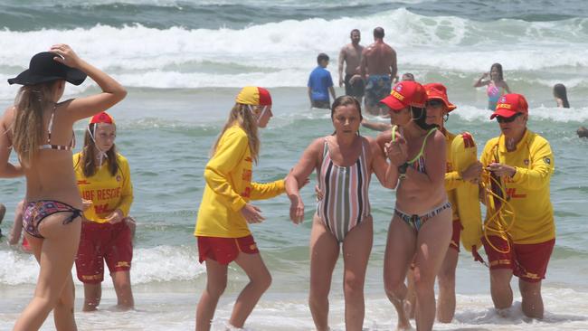 Members of the Palm Beach SLSC Beach patrol help take a woman out of the water. Picture Mike Batterham