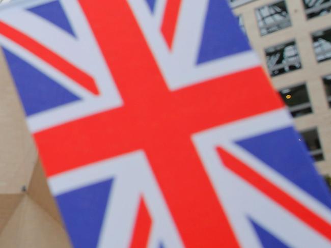 A member of staff stands behind flags as officials arrive for the UK-China High Level Financial Services Roundtable at the Bank of China head office building in Beijing on July 22, 2016. Hammond is in the Chinese capital ahead of the G20 finance ministers' meeting in Chengdu. / AFP PHOTO / POOL / DAMIR SAGOLJ