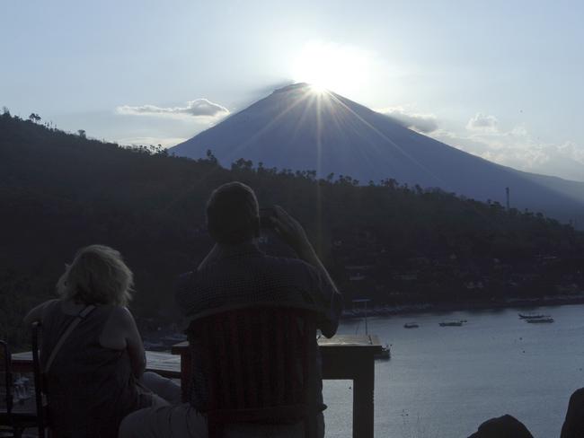 Tourists watch the sunset over Mount Agung in Karangasem on Thursday as Bali braces for the volcano to erupt. Picture: AP/Firdia Lisnawati