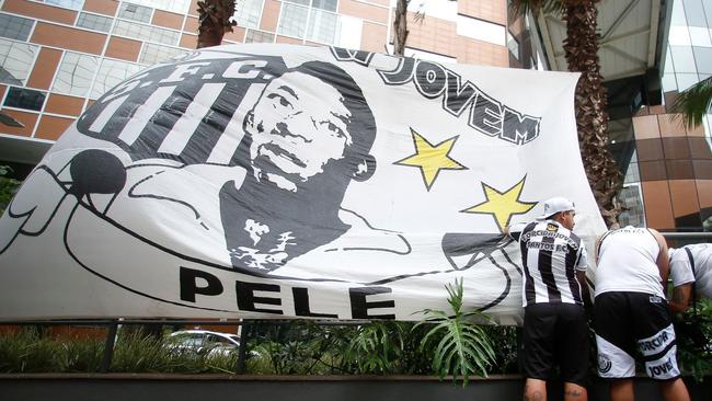 Fans place a flag with the image of Brazilian football legend Pele outside the Albert Einstein Israelite Hospital entrance. Picture: AFP