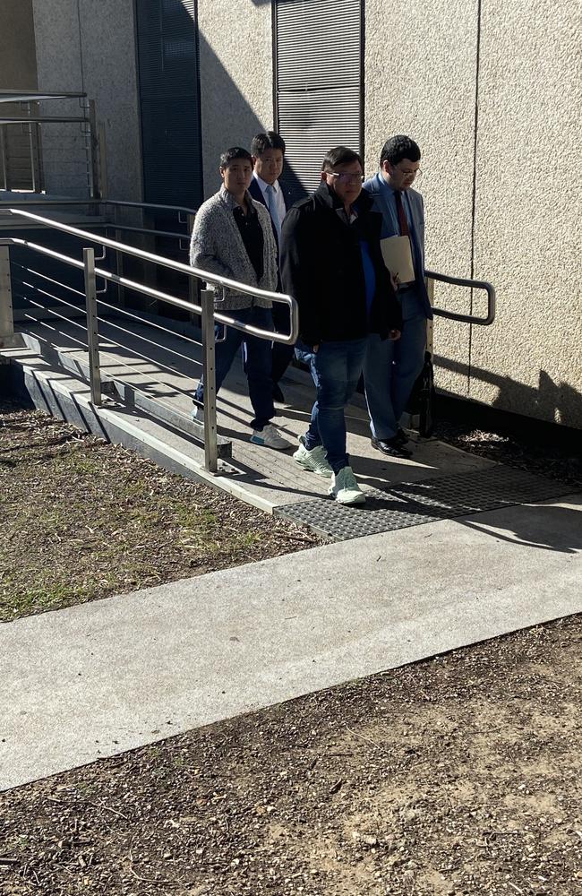 Jenn Huei Ting (third from left, with glasses and wearing a black coat and white runinng shoes) leaves the court with legal counsel.