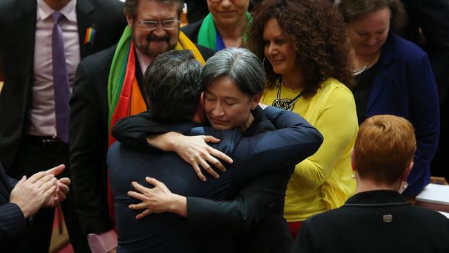 Penny Wong hugs Dean Smith as other Senators celebrate the passing of the bill. Picture: Gary Ramage.