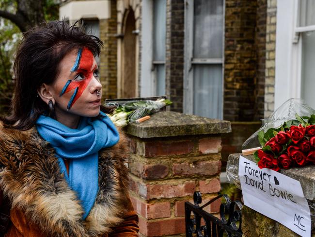 Reflecting ... A fan pays her respects outside a house, believed to be the childhood home of British singer David Bowie, following the announcement of Bowie's death. Picture: AFP Photo/Chris Ratcliffe