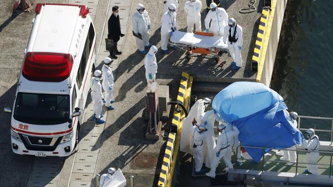 Medical workers lead a passenger who tested positive for a new coronavirus from the cruise ship. Picture: AP