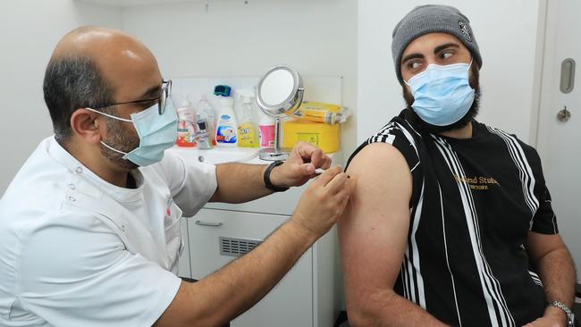 Gregory Lambrousis, 29, receives the AstraZeneca vaccine from chief pharmacist Nadeem Ahmad at Priceline pharmacy in Liverpool in southwest Sydney. Picture: John Feder