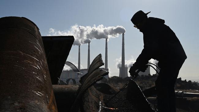 A worker using a torch to cut steel pipes near the coal-powered Datang International Zhangjiakou Power Station at Zhangjiakou. Picture: AFP