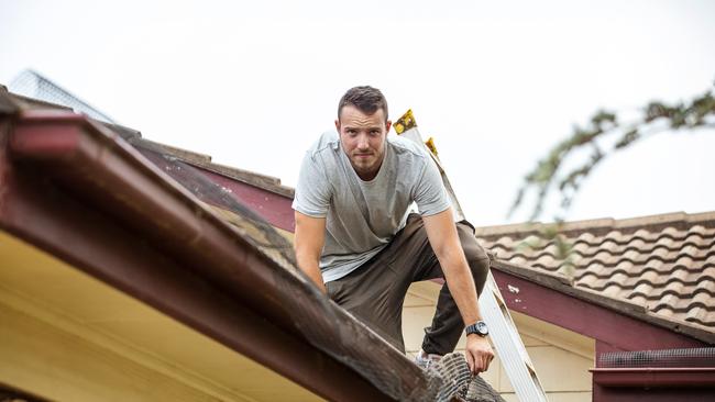 Stephen Grima cleaning the gutters at his parents’ home in preparation for dangerous fire conditions on Tuesday on the 8th of December 2019. Photographer: Adam Yip