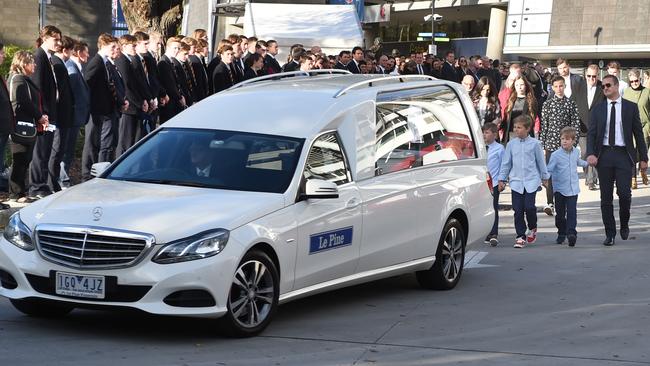 Brad Green and his sons walk behind the hearse carrying his wife after leaving the MCG. Picture: Tony Gough