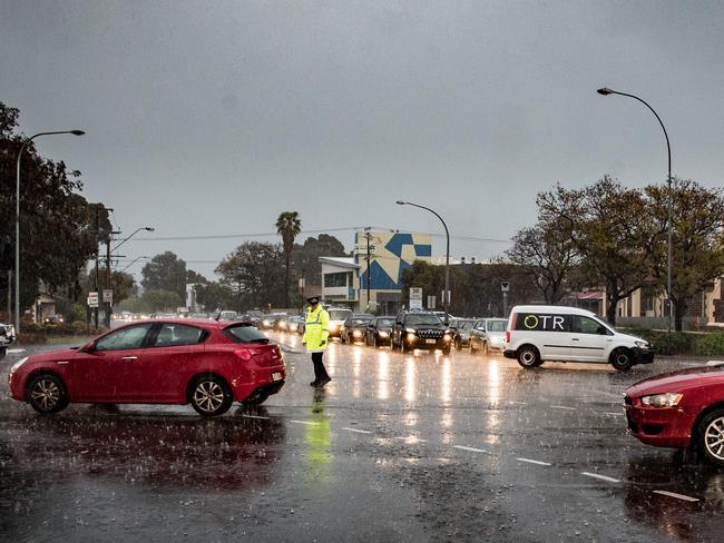 A lone policeman directs traffic in Adelaide after traffic lights went out amid lashing rain and hail. Picture by Matt Turner.