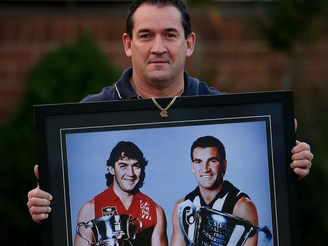 Sean Millane holds a photo of himself with the 1991 Dandenong premiership cup (the year Darren Millane died) and his brother Darren Millane with the Collingwood 1990 premiership cup Picture: Wayne Ludbey