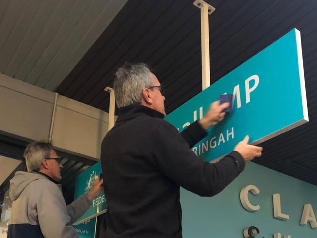 Grant Wiles (left) and his brother Matt, from Absolute Sign Solutions at Brookvale, work to replace the Tony Abbott signs outside the Warringah electorate office in Sydney Rd, Manly, with the distinctive signs of Zali Steggall MP.