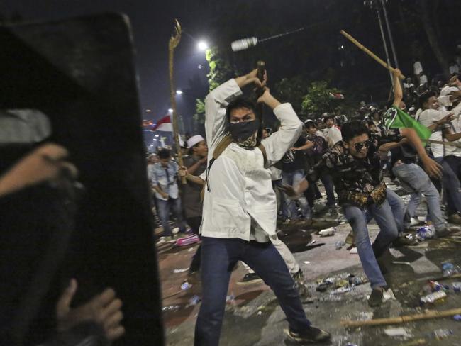 Protesters use sticks to attack riot police during a clash outside the presidential palace in Jakarta, Indonesia. Picture: Tatan Syuflana.