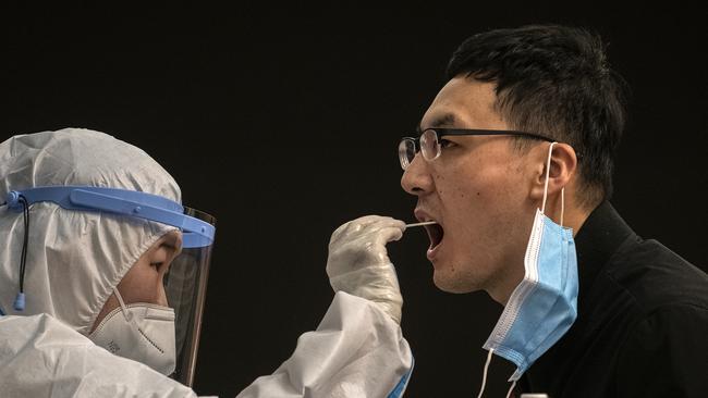 A health worker wears protective equipment as she performs a COVID-19 test before the video press conference of Chinese Foreign Minister Wang Yi. Picture: Getty