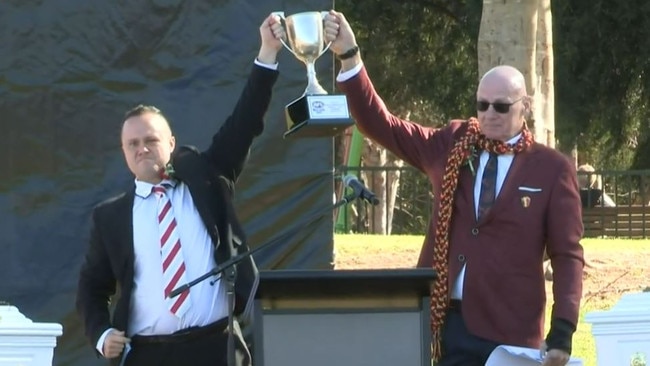 Family friend Alex Tigani raises a premiership cup alongside Mr McBride in honour of the women. Picture: Belinda Jane Video